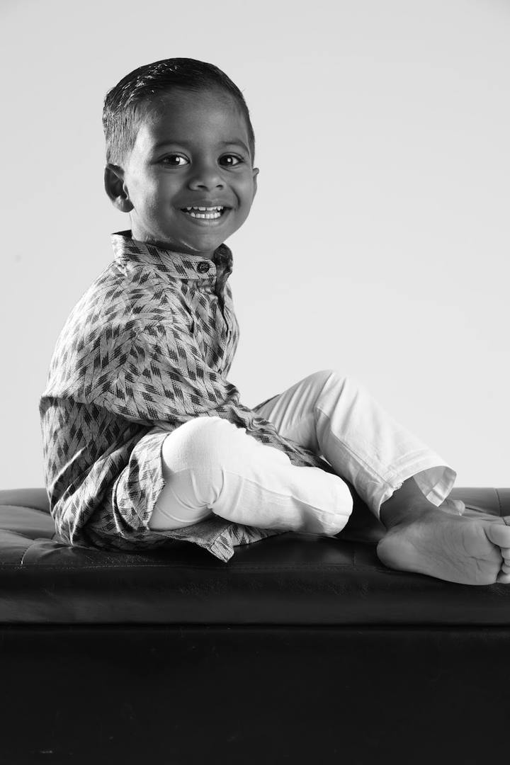 Black and white portrait of Murari seated side‑on on a bench, smiling