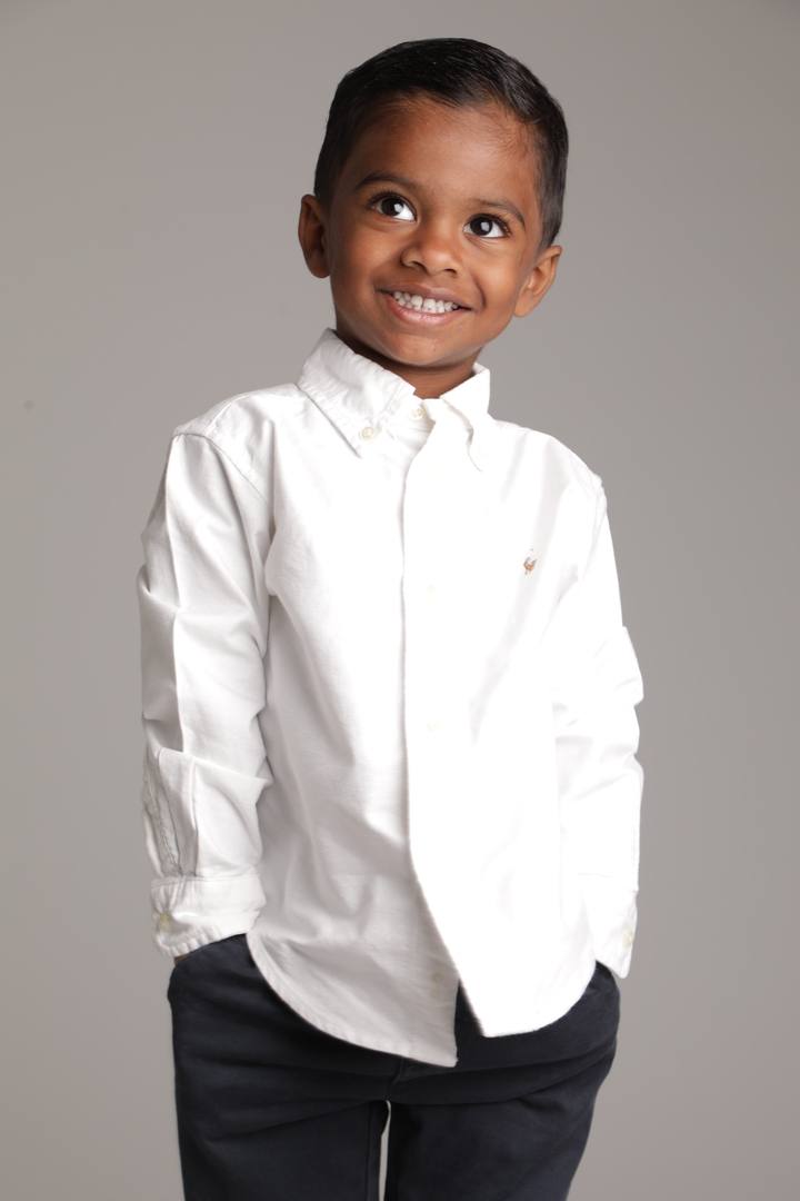 Studio shot of Murari in white shirt smiling, hands in pockets